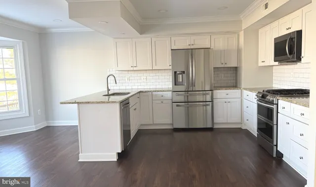 a kitchen with cabinets stainless steel appliances a sink and wooden floor