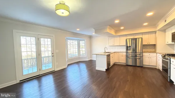 a kitchen with white cabinets and wooden floor