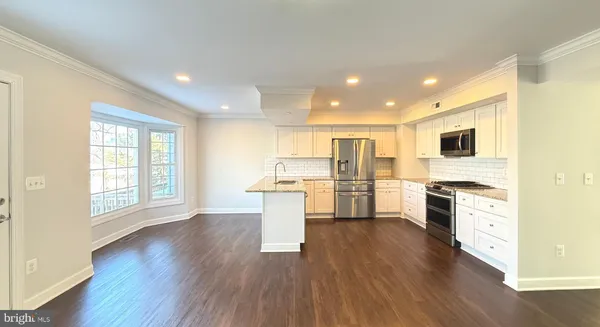 a open kitchen with white cabinets and wooden floor