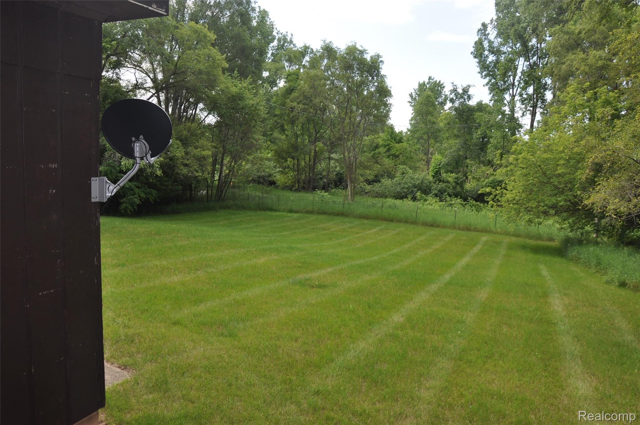 3954 Mayville Road Silverwood, MI 48760 - Photo 9 of 30 Expansive green lawn with visible mowing stripes, bordered by mature trees and natural foliage
