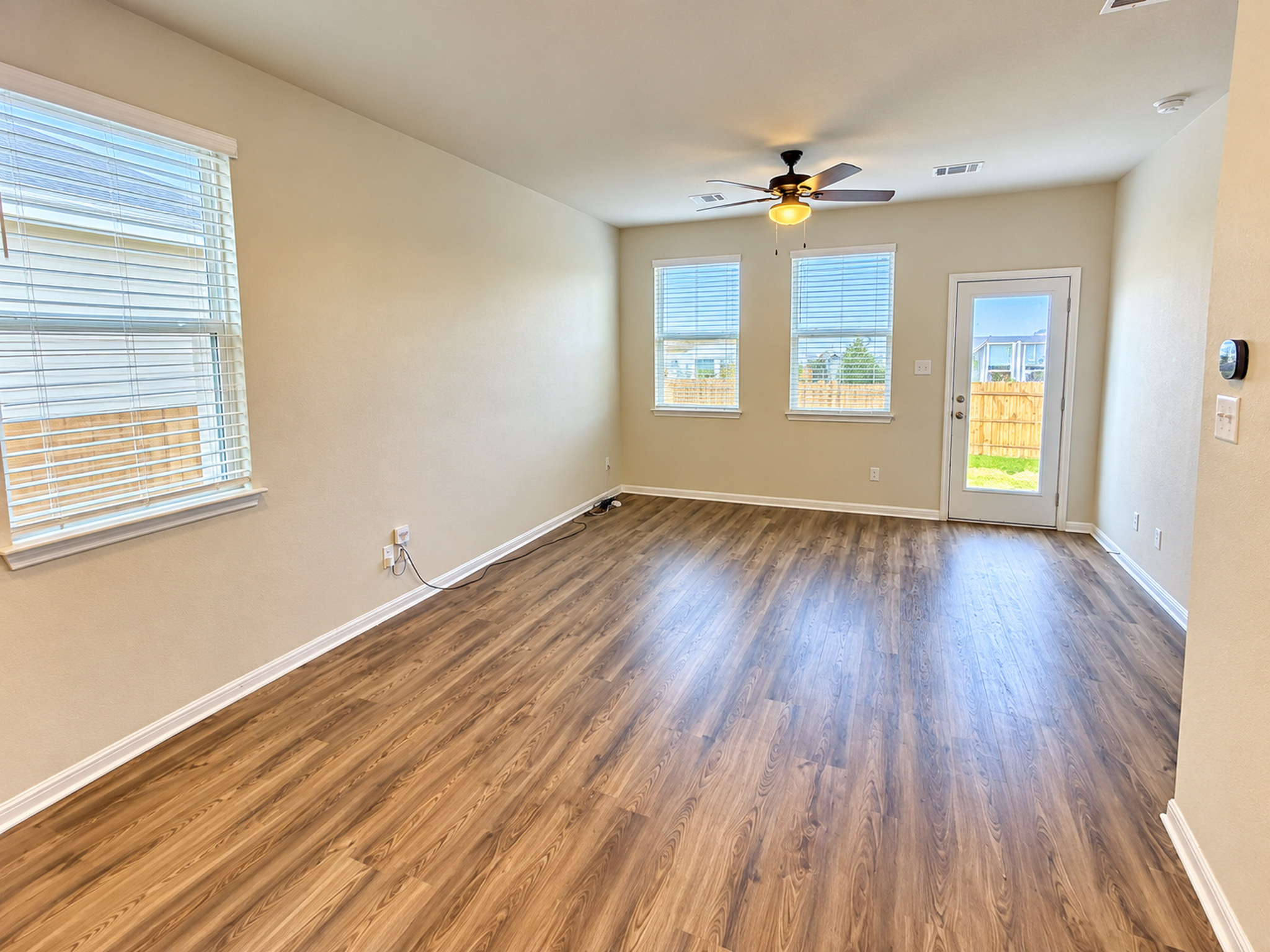 Gleaming wood-look floors anchor this versatile room complete with a glass door to the backyard.