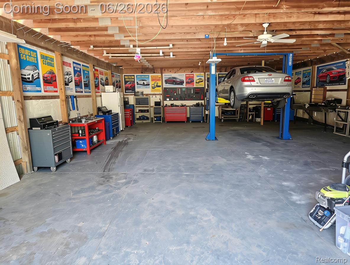 5366 East Mt Morris Road Mount Morris, MI 48458 - Photo 50 of 57 AI Edited Spacious garage featuring a vehicle lift, exposed beam ceiling, multiple workbenches, dedicated storage areas, and concrete flooring