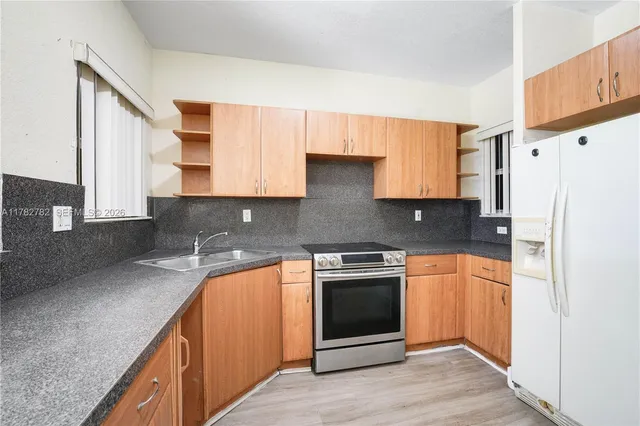 a kitchen with stainless steel appliances granite countertop a stove a sink and a refrigerator