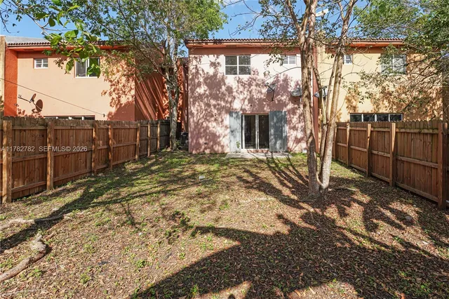 a view of a backyard with large trees and wooden fence