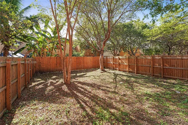a view of a backyard with wooden fence and a large tree