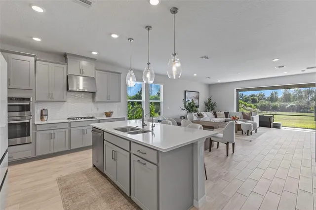 a large kitchen with kitchen island a sink a stove a dining table and chairs