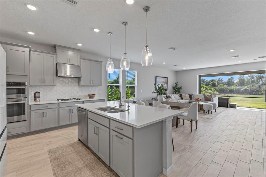 5679 Blue Reef Place Nokomis, FL 34275 - Photo 15 of 46 a large kitchen with kitchen island a sink a stove a dining table and chairs
