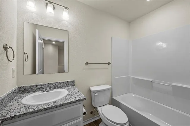 a bathroom with a granite countertop toilet sink and mirror