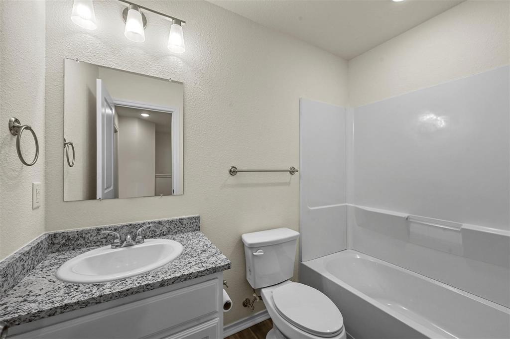 105 Southeast 4th Street, Unit 1 Kerens, TX 75144 - Photo 13 of 23 a bathroom with a granite countertop toilet sink and mirror