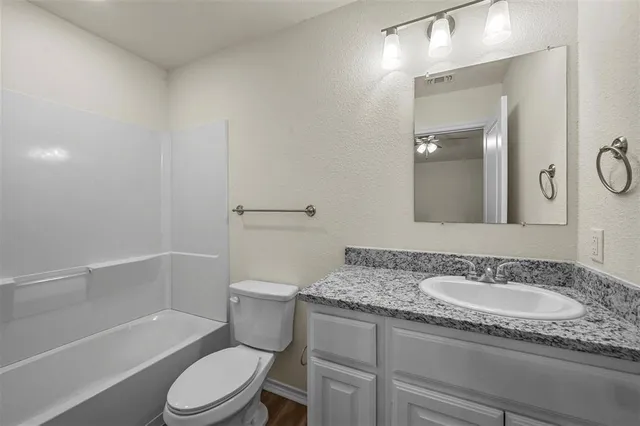 a bathroom with a granite countertop sink a toilet and shower