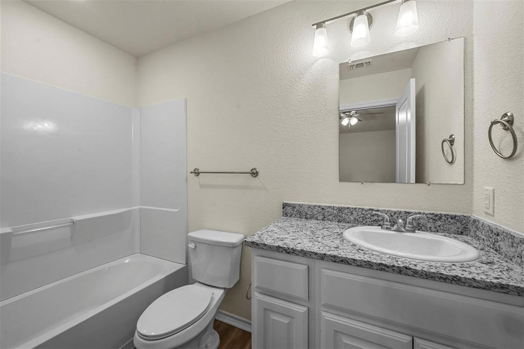 105 Southeast 4th Street, Unit 1 Kerens, TX 75144 - Photo 14 of 23 a bathroom with a granite countertop sink a toilet and shower