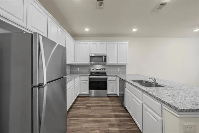 a kitchen with granite countertop a refrigerator and a sink