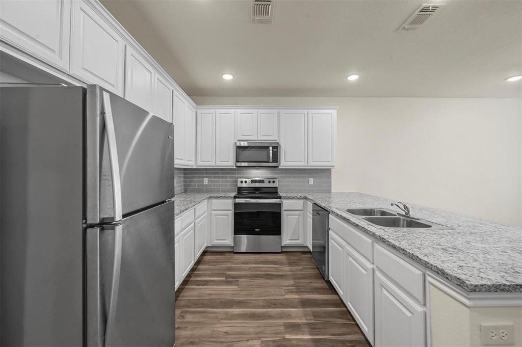 105 Southeast 4th Street, Unit 1 Kerens, TX 75144 - Photo 2 of 23 a kitchen with granite countertop a refrigerator and a sink