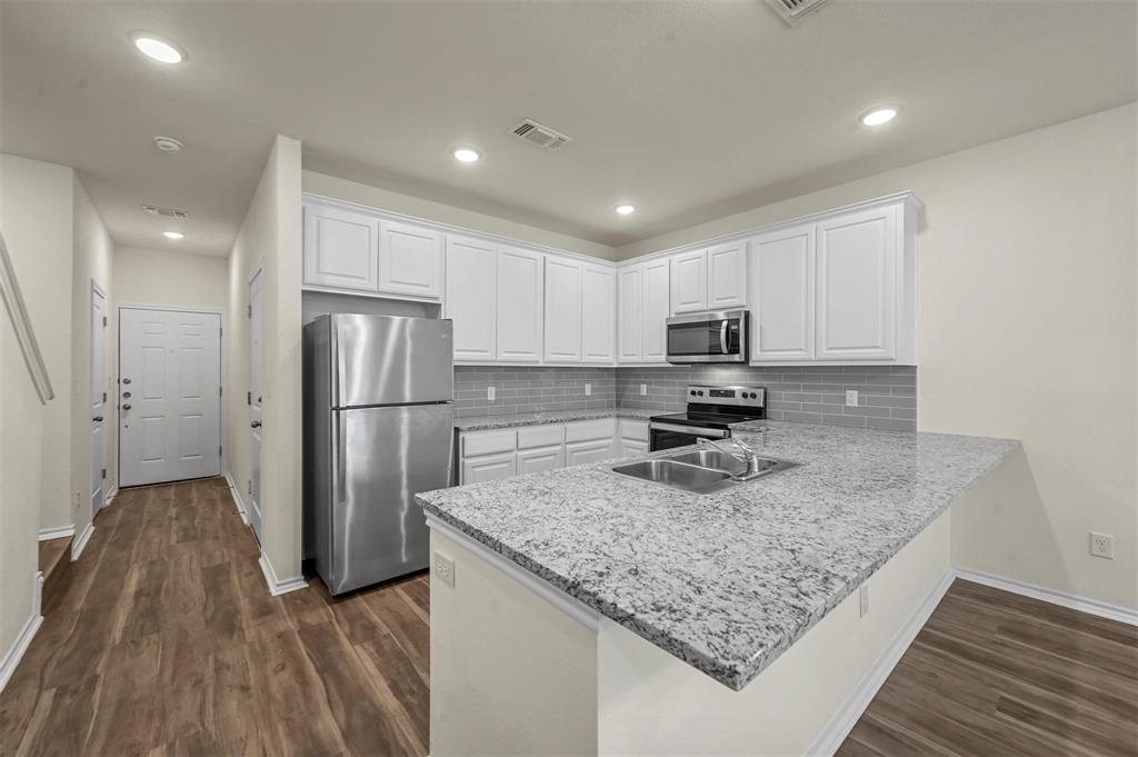 105 Southeast 4th Street, Unit 1 Kerens, TX 75144 - Photo 4 of 23 a kitchen with refrigerator cabinets and wooden floor