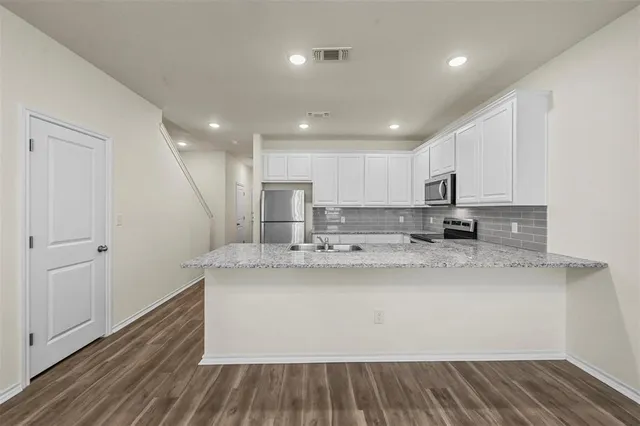 a view of kitchen with stainless steel appliances granite countertop cabinets and wooden floor