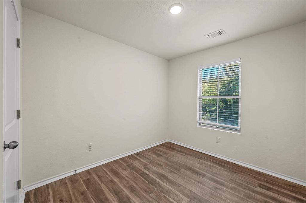 105 Southeast 4th Street, Unit 1 Kerens, TX 75144 - Photo 8 of 23 an empty room with wooden floor and windows