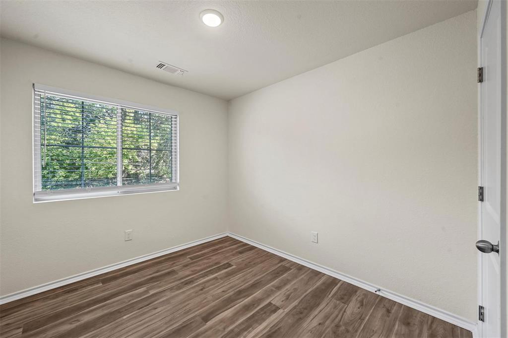 105 Southeast 4th Street, Unit 1 Kerens, TX 75144 - Photo 9 of 23 an empty room with wooden floor and windows