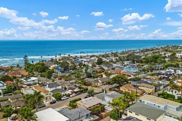 an aerial view of a city with lots of residential buildings and ocean view in back