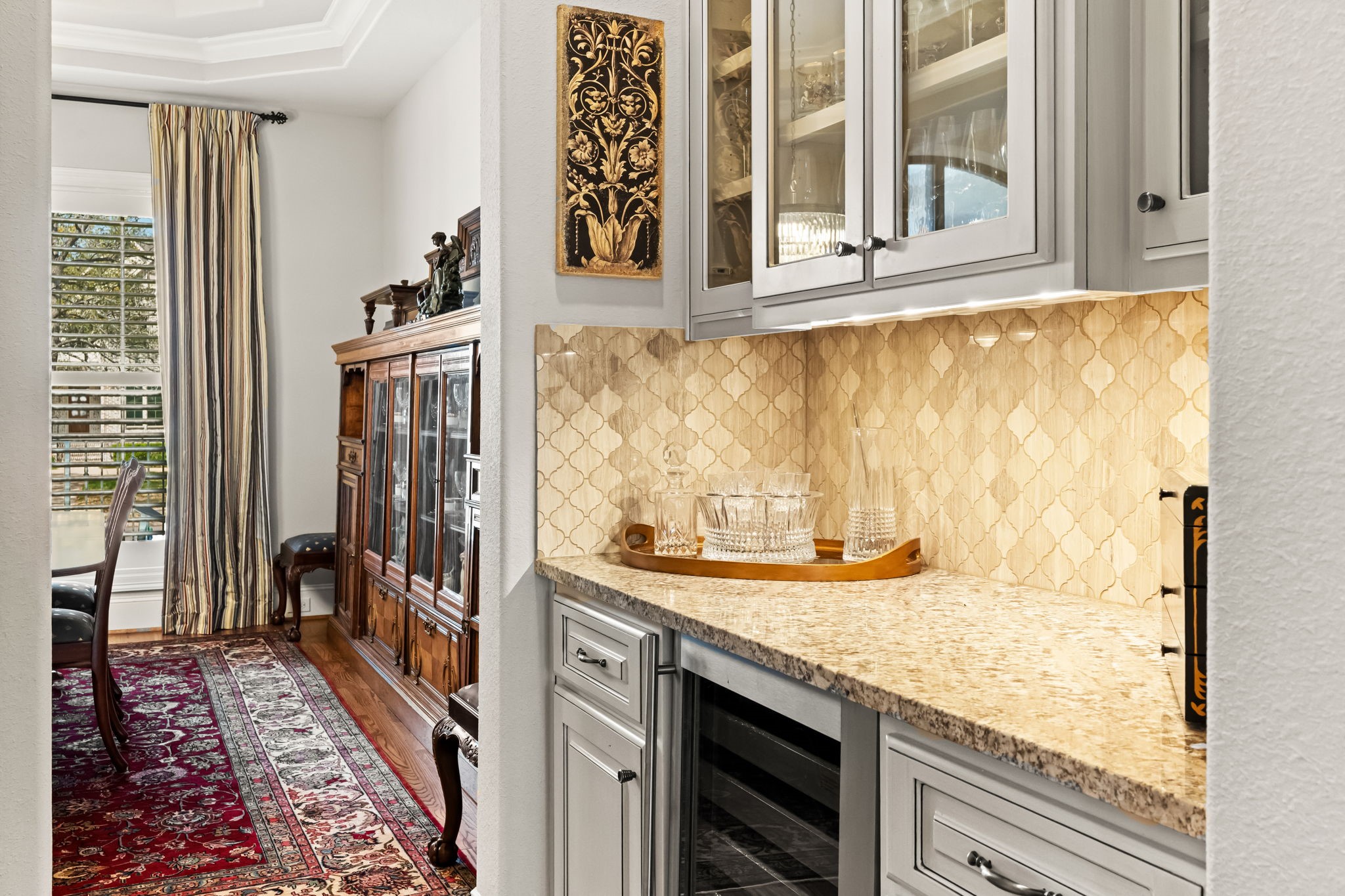4823 Jason Street Houston, TX 77096 - Photo 15 of 40 This photo showcases a cozy butler's pantry with elegant cabinetry and granite countertops. It is perfectly situated between the dining area and the kitchen.
