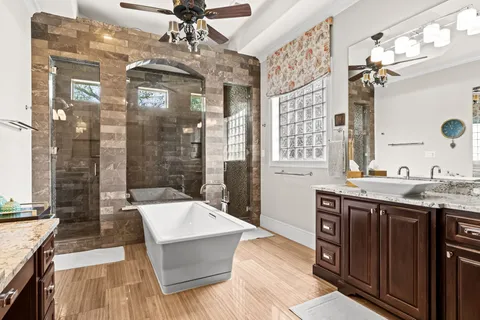 a spacious bathroom with a tub sink shower and mirror
