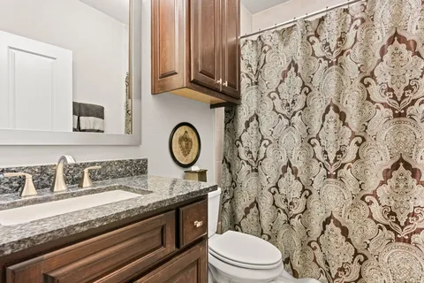 a bathroom with a granite countertop sink and a toilet