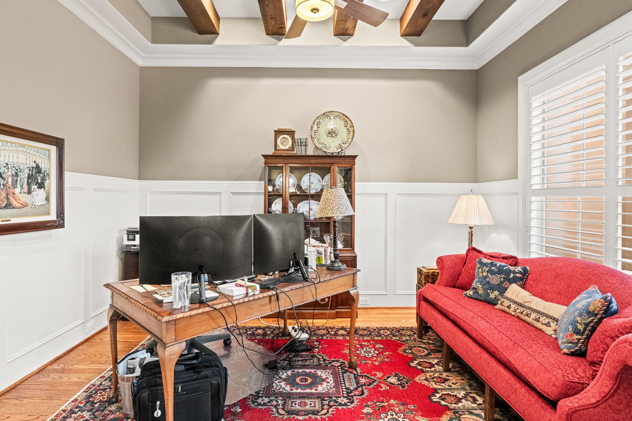 4823 Jason Street Houston, TX 77096 - Photo 6 of 40 This cozy home office features elegant wood-beamed ceilings, wainscoting, and hardwood floors. Natural light filters through plantation shutters, creating an inviting atmosphere.