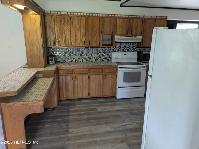 a kitchen with granite countertop a sink stove and refrigerator