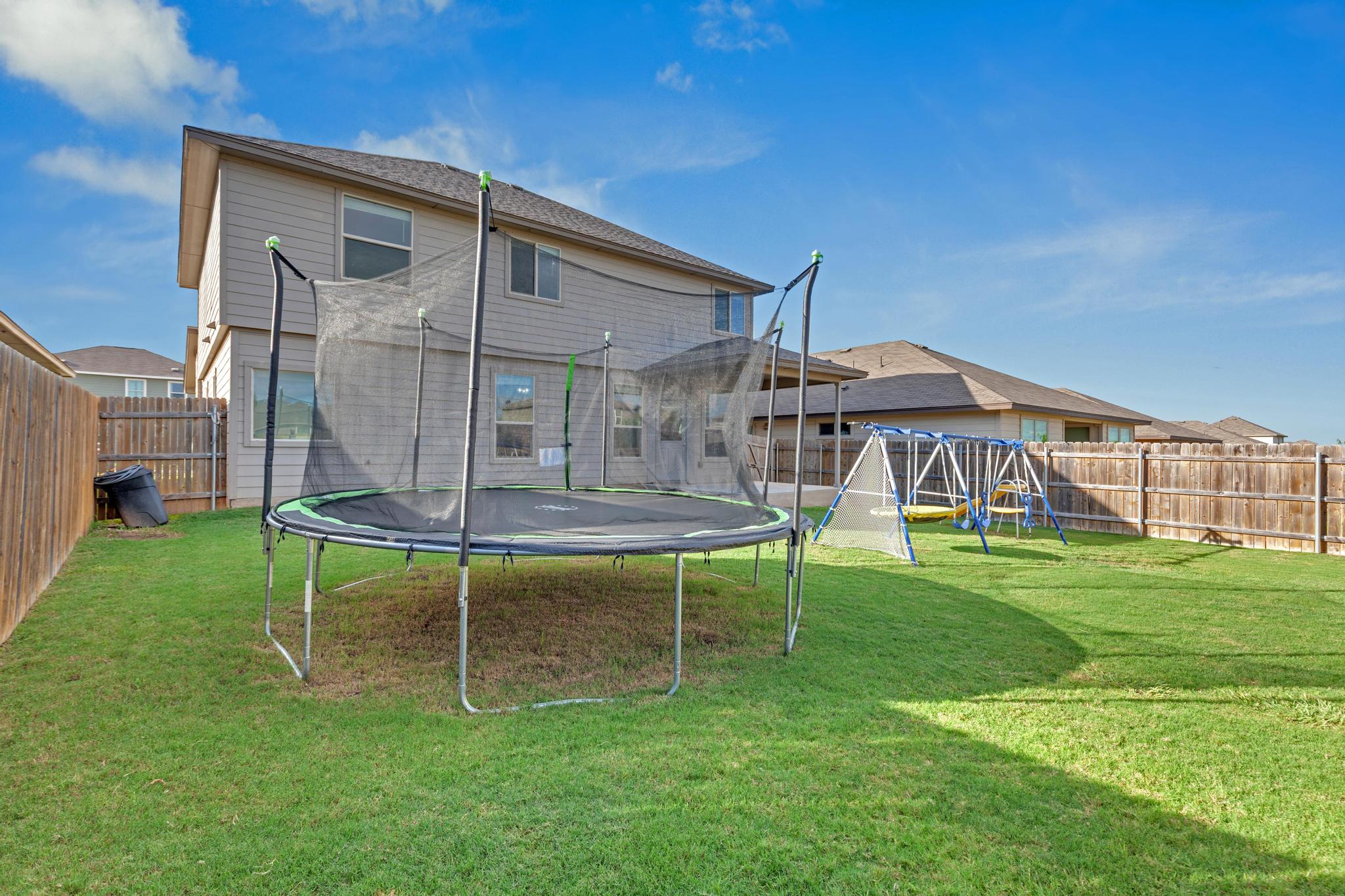 104 Uncle Billy Way Jarrell, TX 76537 - Photo 35 of 38 A spacious, well-maintained backyard featuring a play set and a trampoline, fully fenced for privacy.