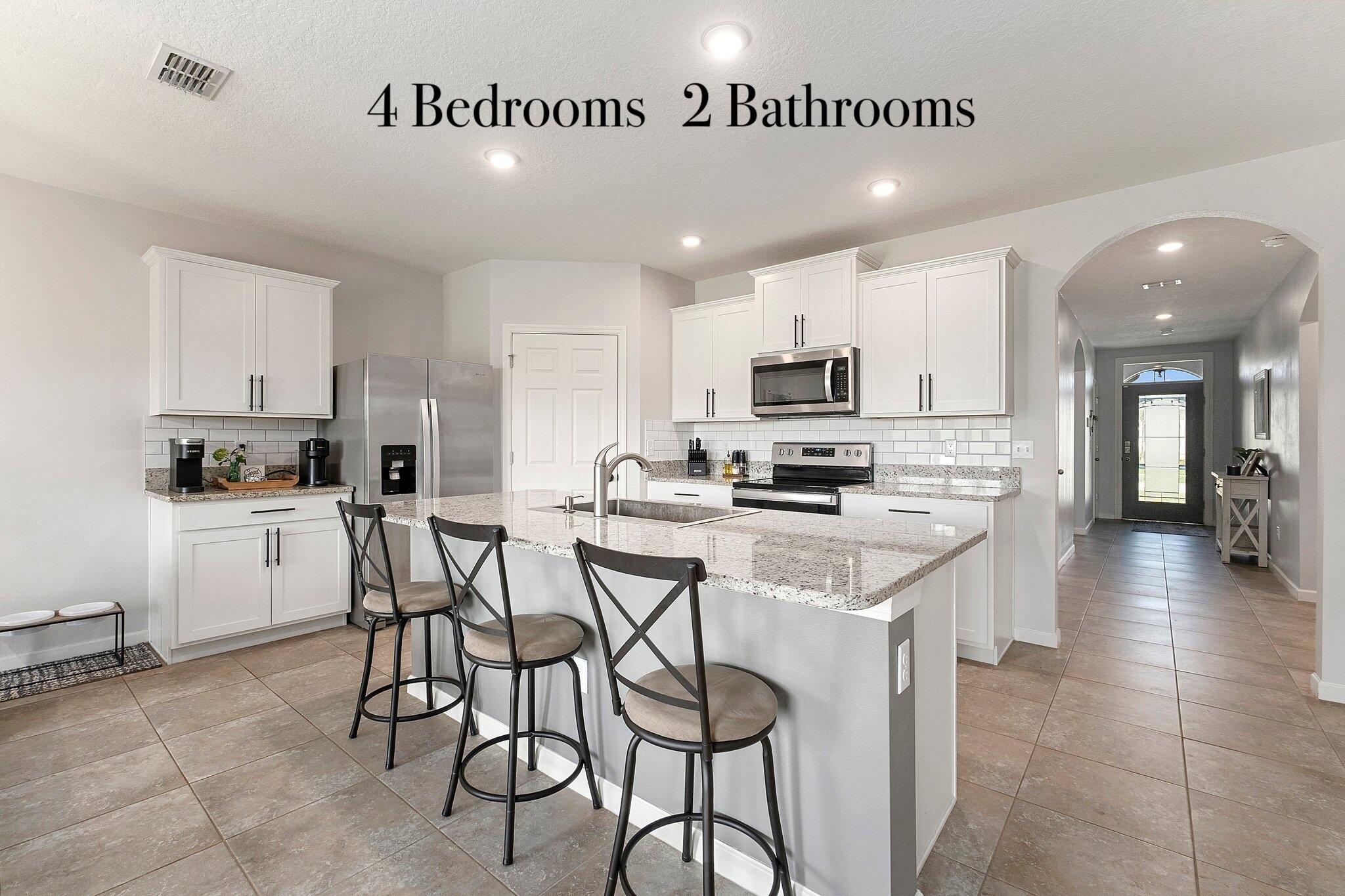 10850 Pacini Way Port St. Lucie, FL 34987 - Photo 35 of 36 a kitchen with stainless steel appliances kitchen island granite countertop a stove a sink a refrigerator and white cabinets with wooden floor