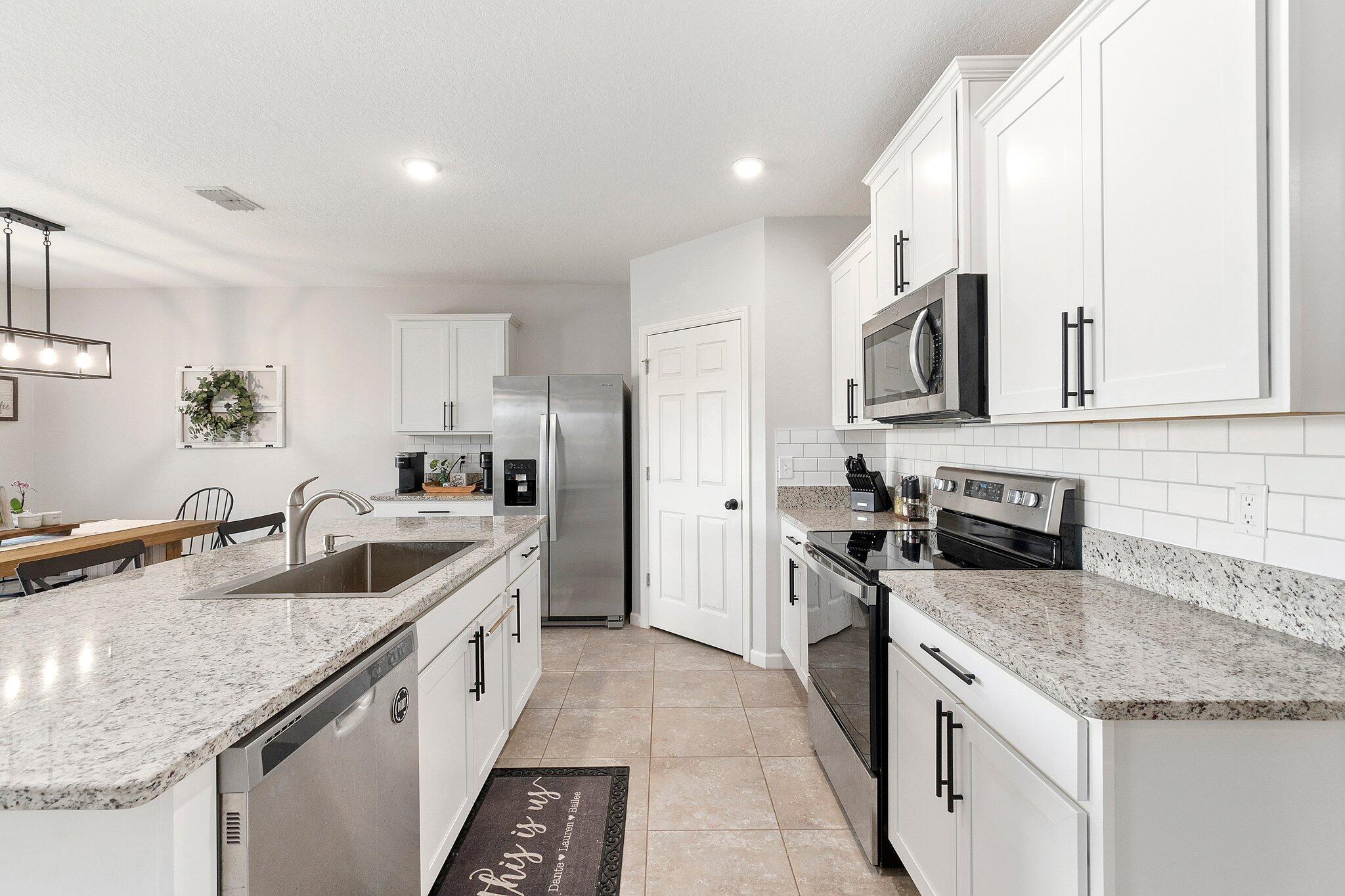 10850 Pacini Way Port St. Lucie, FL 34987 - Photo 10 of 36 a kitchen with stainless steel appliances granite countertop a sink stove and refrigerator