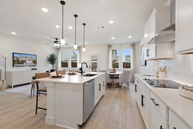 a large kitchen with lots of counter space a sink appliances and a living room view