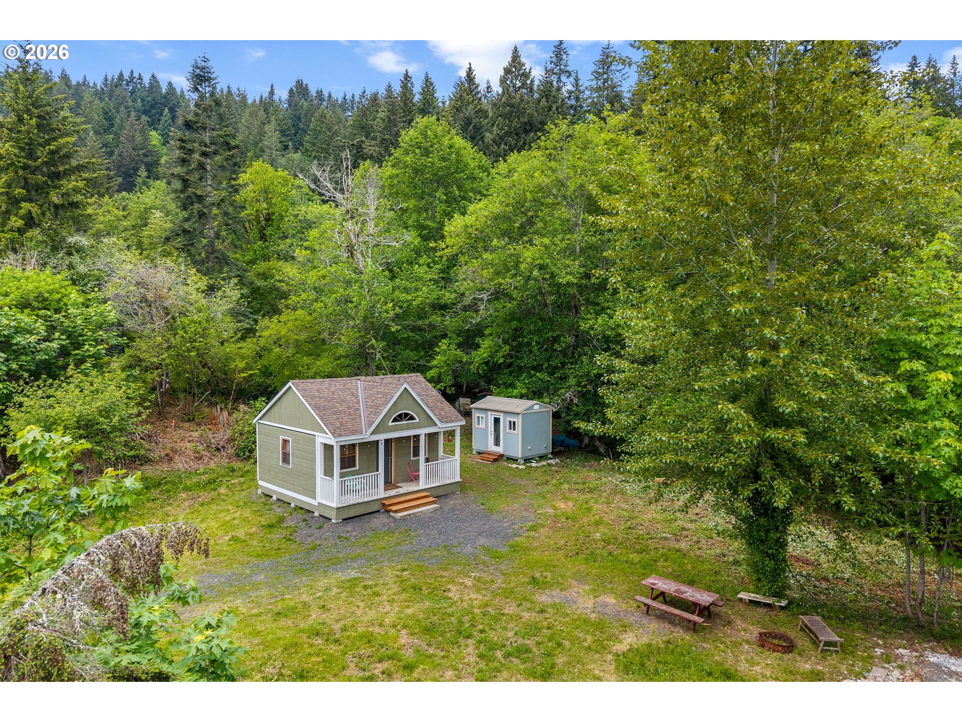 91 Rancho Del Oro Road Stevenson, WA 98648 - Photo 5 of 19 a white house with a small yard and large trees