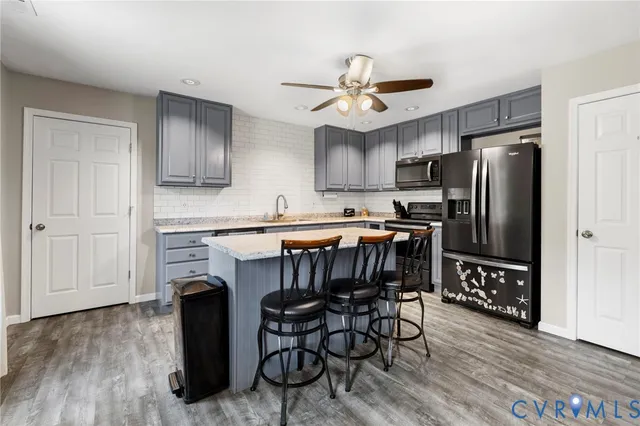 a kitchen with granite countertop a refrigerator stove a sink and dishwasher with wooden floor