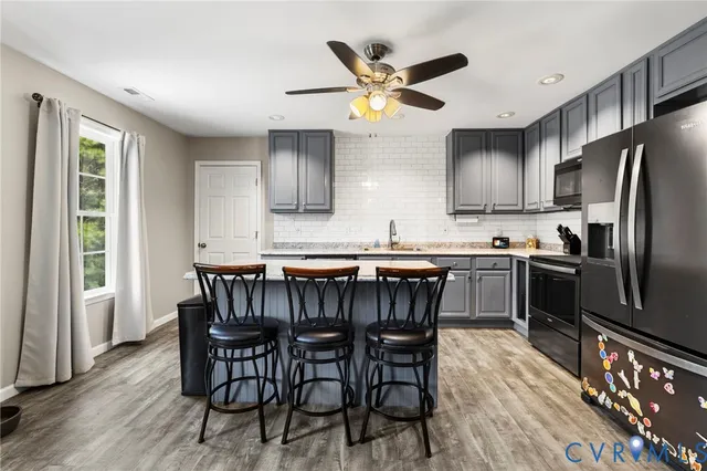a kitchen with stainless steel appliances a table chairs refrigerator and microwave