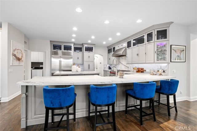 a kitchen with stainless steel appliances kitchen island granite countertop a table chairs sink and cabinets