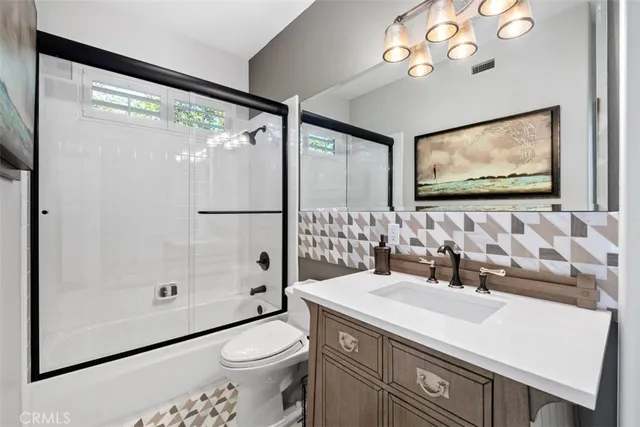 a bathroom with a sink a toilet a mirror a vanity and shower