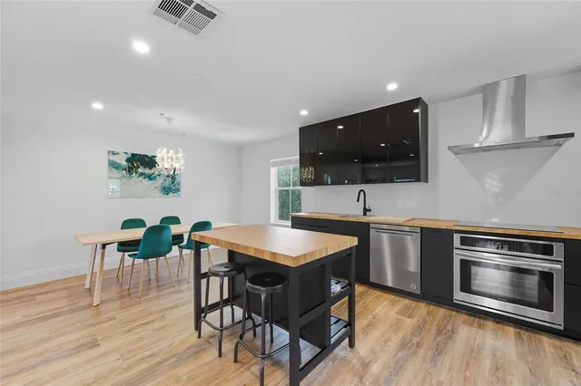 a kitchen with stainless steel appliances granite countertop a stove a sink a microwave a dining table and chairs with wooden floor