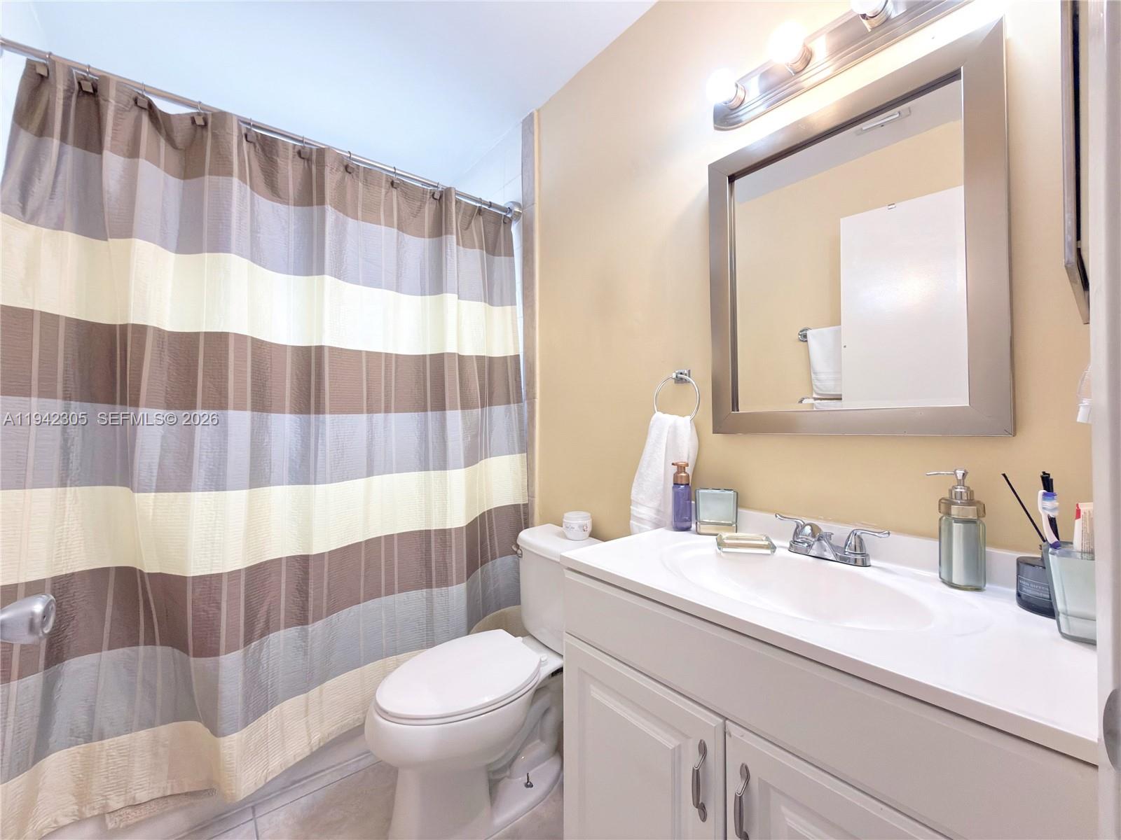 14911 Southwest 80th Street, Unit 221 Miami, FL 33193 - Photo 17 of 31 a bathroom with a sink a toilet a mirror and shower curtain