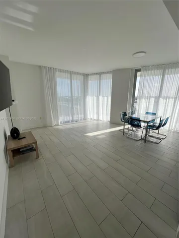 a living room with furniture wooden floor and a large window