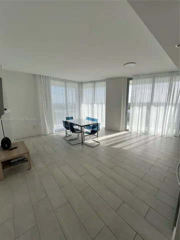 a view of a hallway with wooden floor and a bathroom