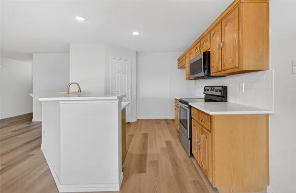 a hallway with stainless steel appliances granite countertop a sink a stove a microwave a counter top space and cabinets