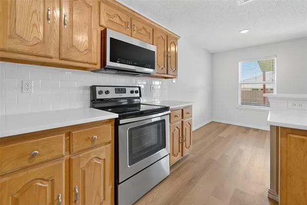 a kitchen with stainless steel appliances granite countertop a sink a stove a microwave oven cabinets and wooden floor