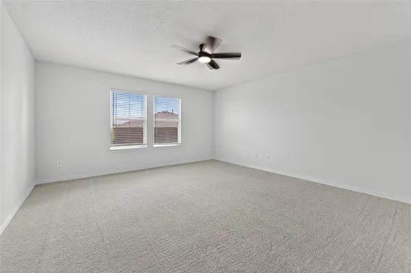 an empty room with windows and ceiling fan