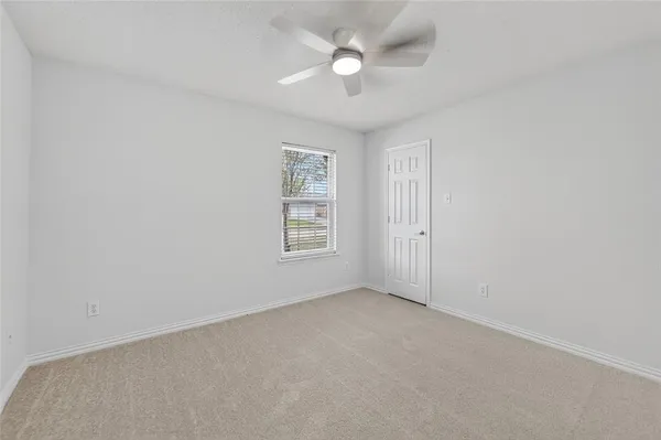an empty room with a window and ceiling fan
