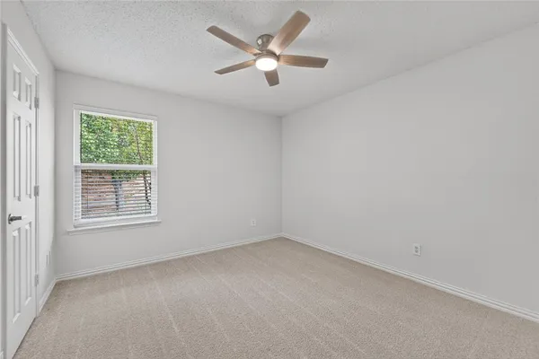 an empty room with a window and a ceiling fan