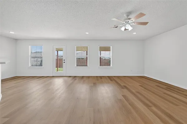 a view of an empty room with wooden floor and window