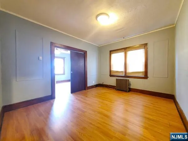 a view of an empty room with window and wooden floor