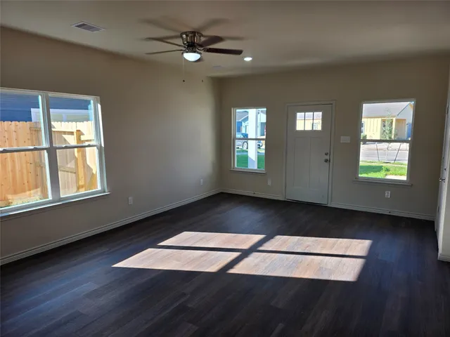 a view of an empty room with wooden floor and a window