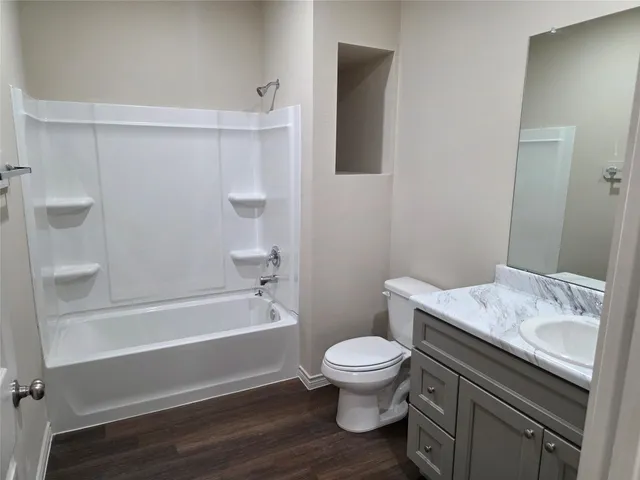 a bathroom with a granite countertop toilet and a bathtub