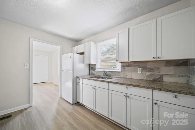 a kitchen with stainless steel appliances granite countertop a refrigerator sink and white cabinets